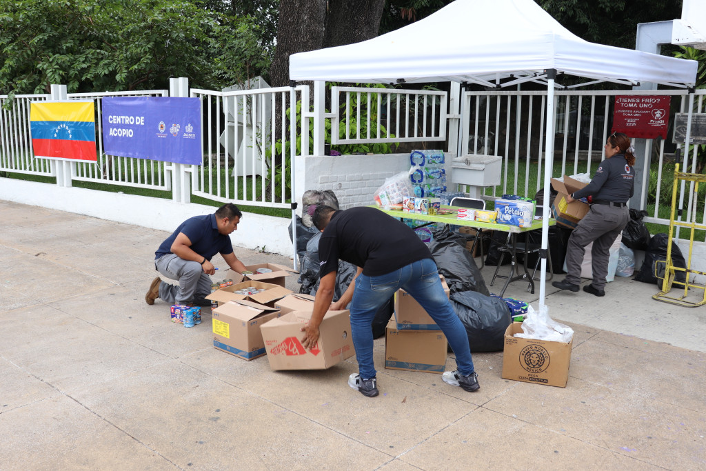 Personal de PC DIF cuenta artículos de primer donativo recibido en el centro de acopio ubicado al ingreso principal de oficinas centrales al fondo se observa la bandera de Venezuela